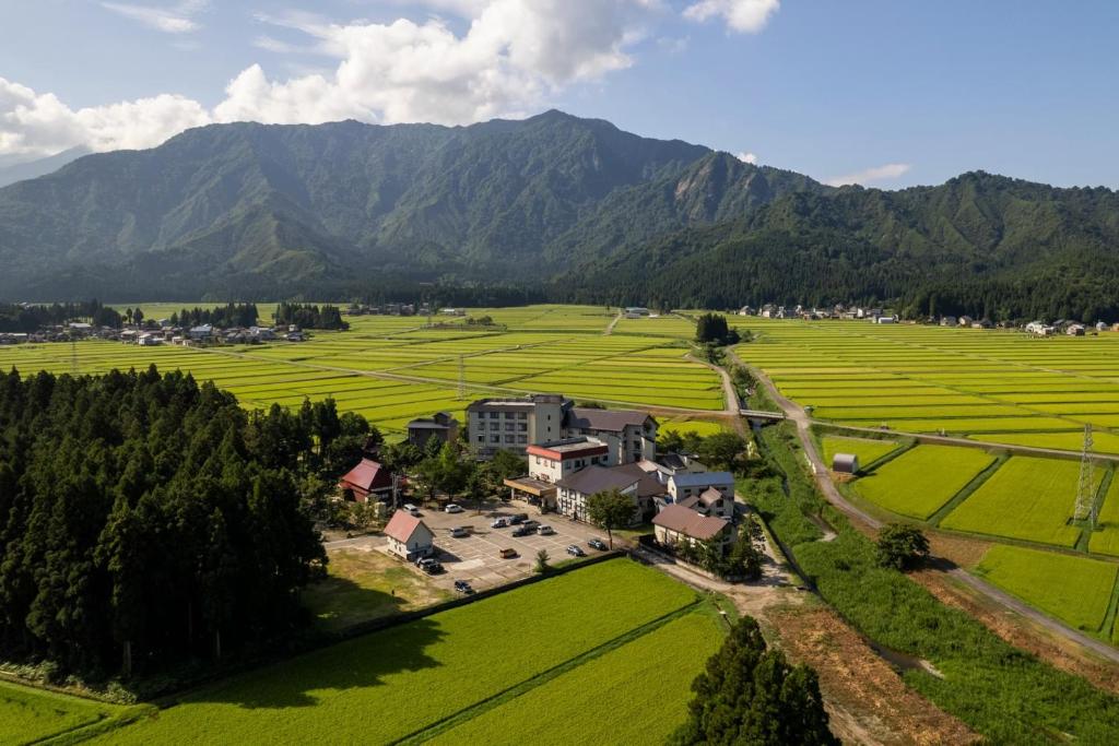 an aerial view of a farm with mountains in the background at IkazawaYumotokan in Minami Uonuma