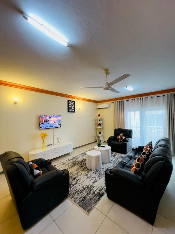 a living room with two black couches and a tv at SPACIOUS 2 AND 3 BEDROOM APARTMENTs in Mtwapa