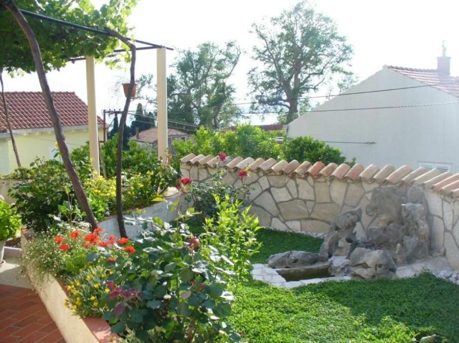 a garden with flowers and a stone wall at Radovčić Apartments and Rooms in Trsteno