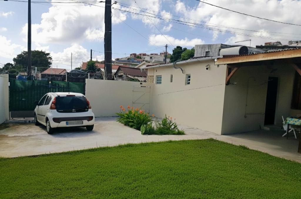 un'auto parcheggiata in un parcheggio accanto a una casa di L'escale Foyalaise - wifi, clim, jardin créole, parking privatif a Fort-de-France