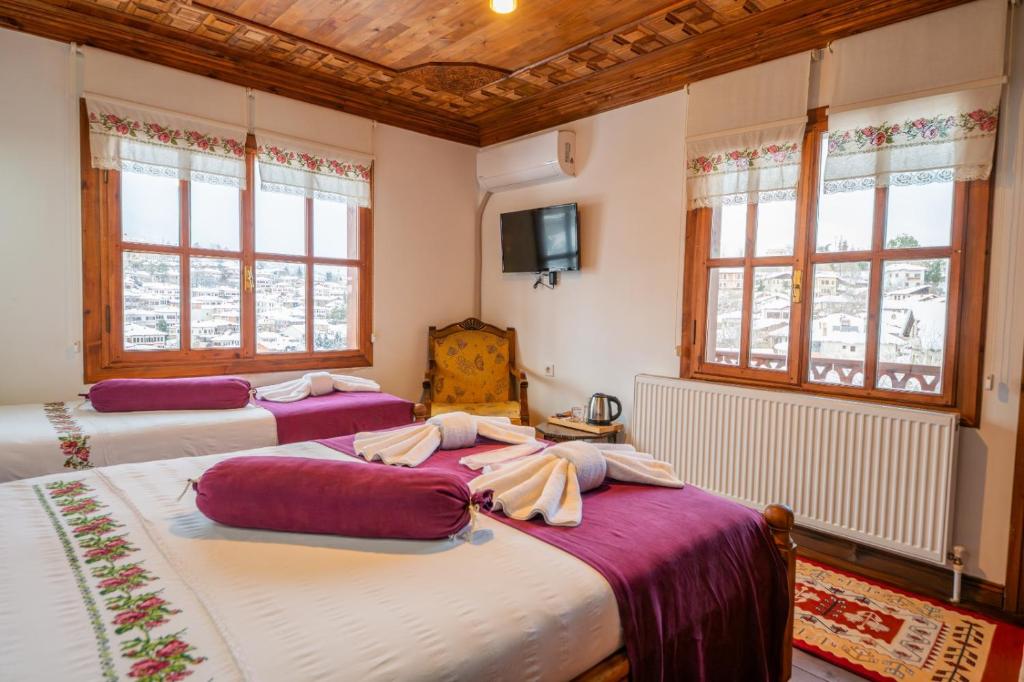 two beds in a room with windows and a tv at Manzara Konak Otel in Safranbolu