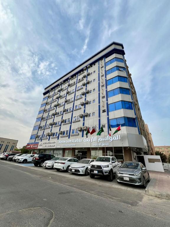 a large building with cars parked in a parking lot at Almawasem Alarbaa for Serviced Apartments - Standard in Al Jubail