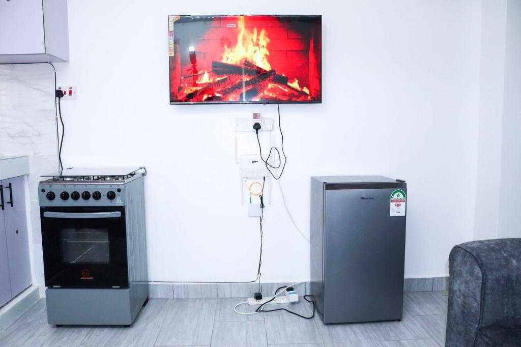 a kitchen with a stove and a tv on the wall at Raels home in Mombasa
