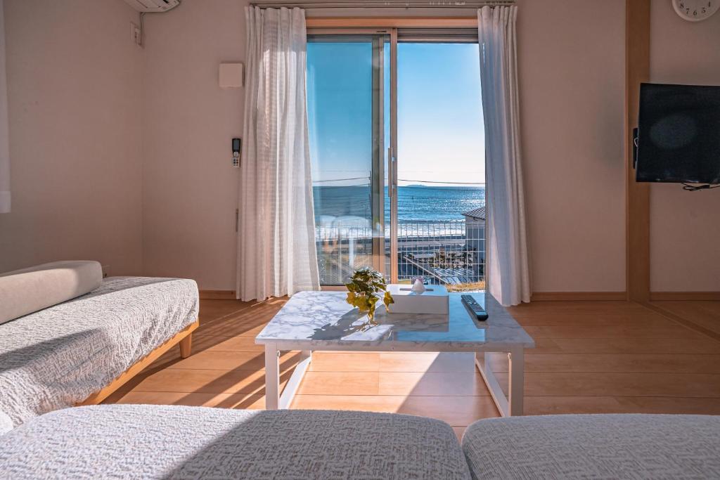 a living room with a table and a view of the ocean at 波音ハウス湯河原ー心地よい波Waveの音に包まれる癒しの別荘BBQ可 in Yugawara