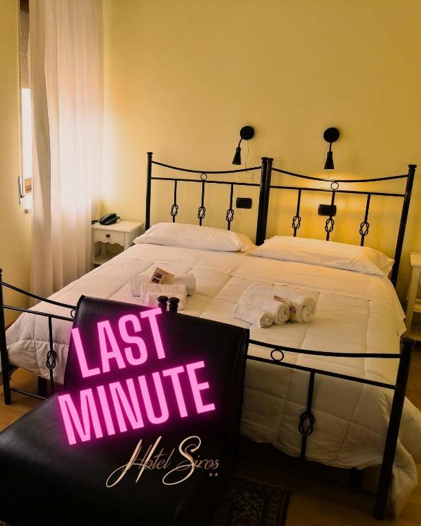 un letto grande con un cartello dell'ultimo minuto sopra di Hotel Siros a Verona
