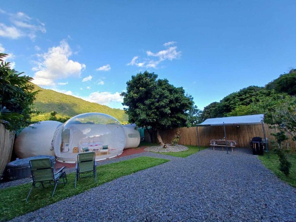 een achtertuin met een tent en stoelen en een boom bij Entre 2 bulles in Entre-Deux