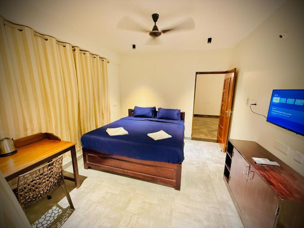 a bedroom with a blue bed and a television at Villa Govindaraj in Pondicherry