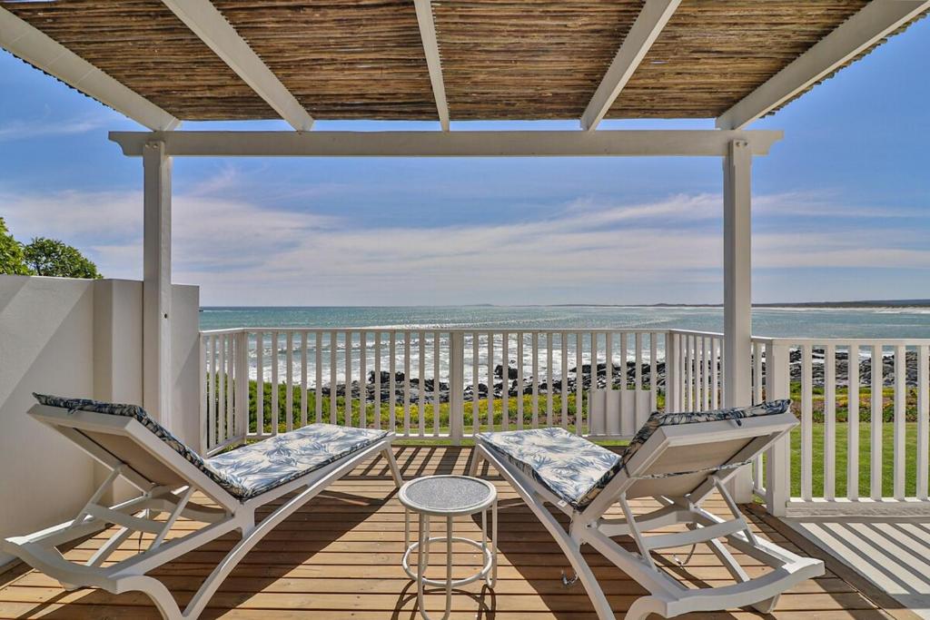 a porch with two chairs and a table and the ocean at On the Rocks in Yzerfontein
