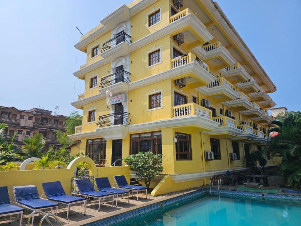 a yellow building with chairs next to a swimming pool at Sonikas Leisure in Candolim
