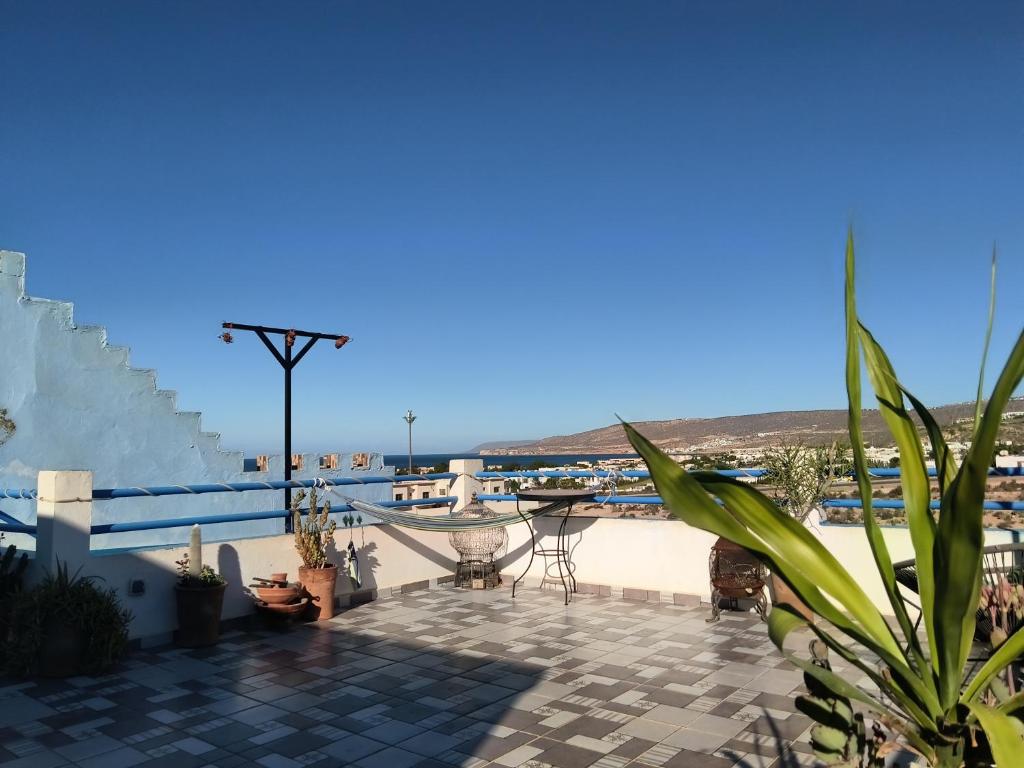 een patio met een tafel en stoelen en uitzicht op de oceaan bij Nova surf house in Tamraght Ou Fella