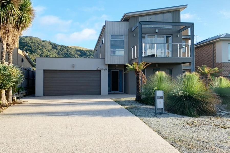 a house with a garage and palm trees at Large Five Bdrm Home Near Beach in Apollo Bay