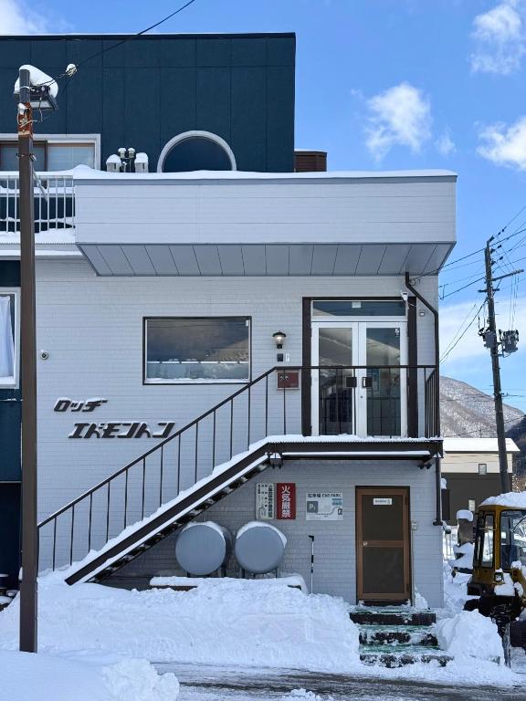 a white building with a staircase in the snow at lodge EDMONTON in Yuzawa