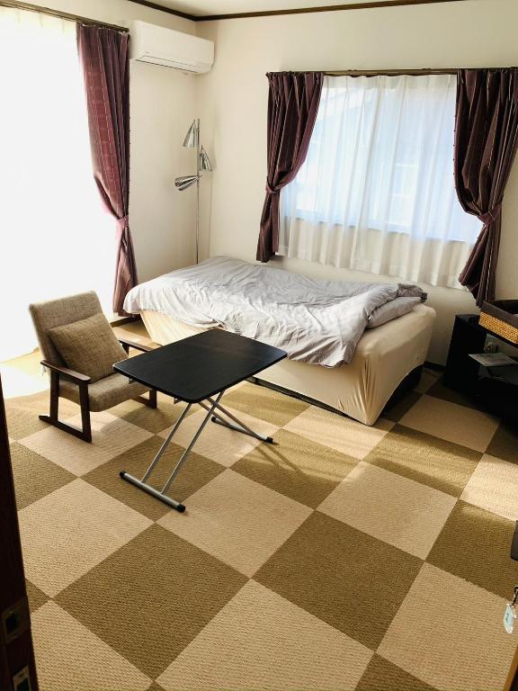 a bedroom with a bed and a table and a chair at れのん in Okazaki