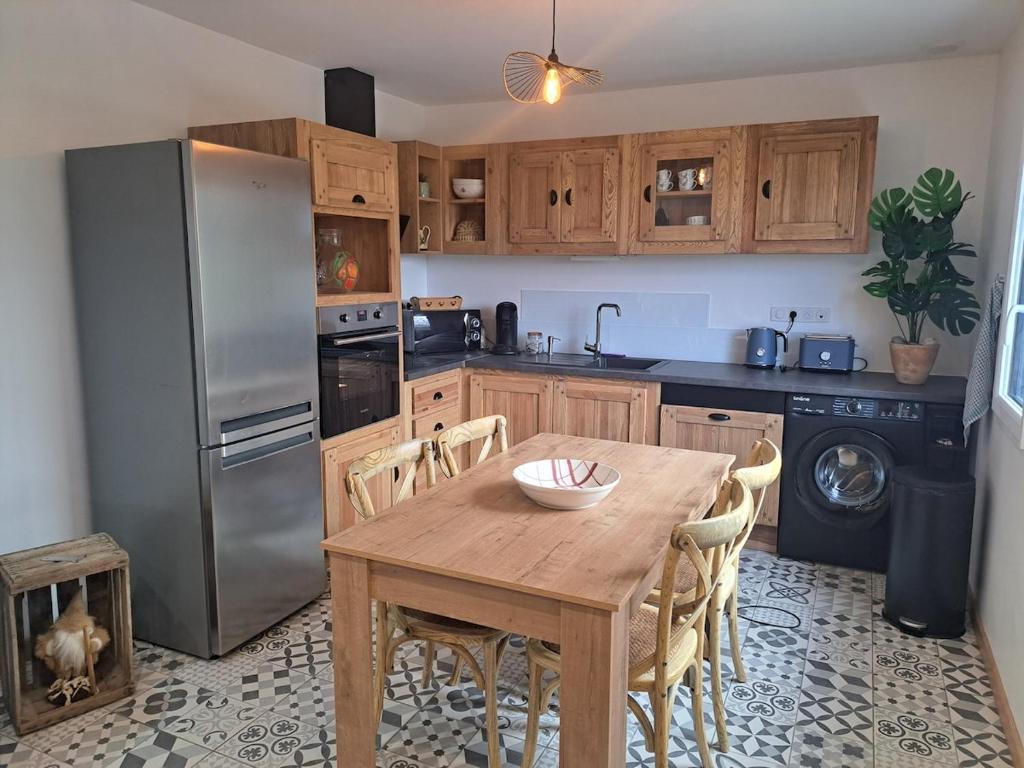 a kitchen with a wooden table and a stainless steel refrigerator at La maison d'à côté in Desingy