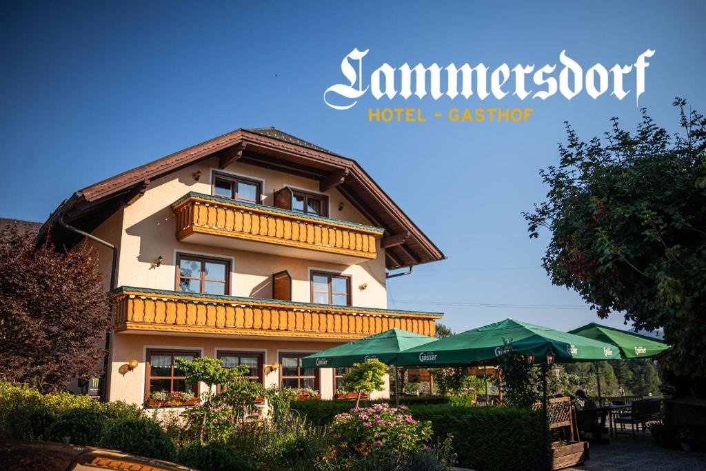 a building with a balcony and some green umbrellas at Hotel-Gasthof Lammersdorf in Millstatt
