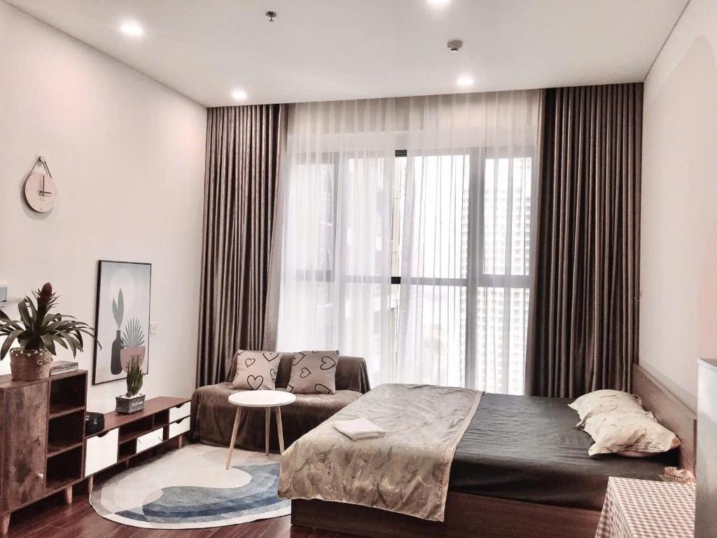 a bedroom with a bed and a couch and a window at Capsule Masterise Vinhomes in Gia Lâm Pho