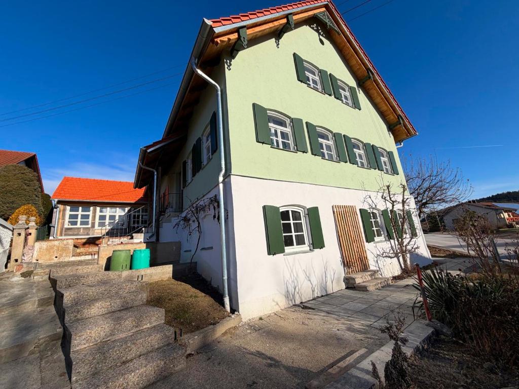 a white and green house with green shutters at Ferienhaus Winterbach - Alte Käserei in Winterbach