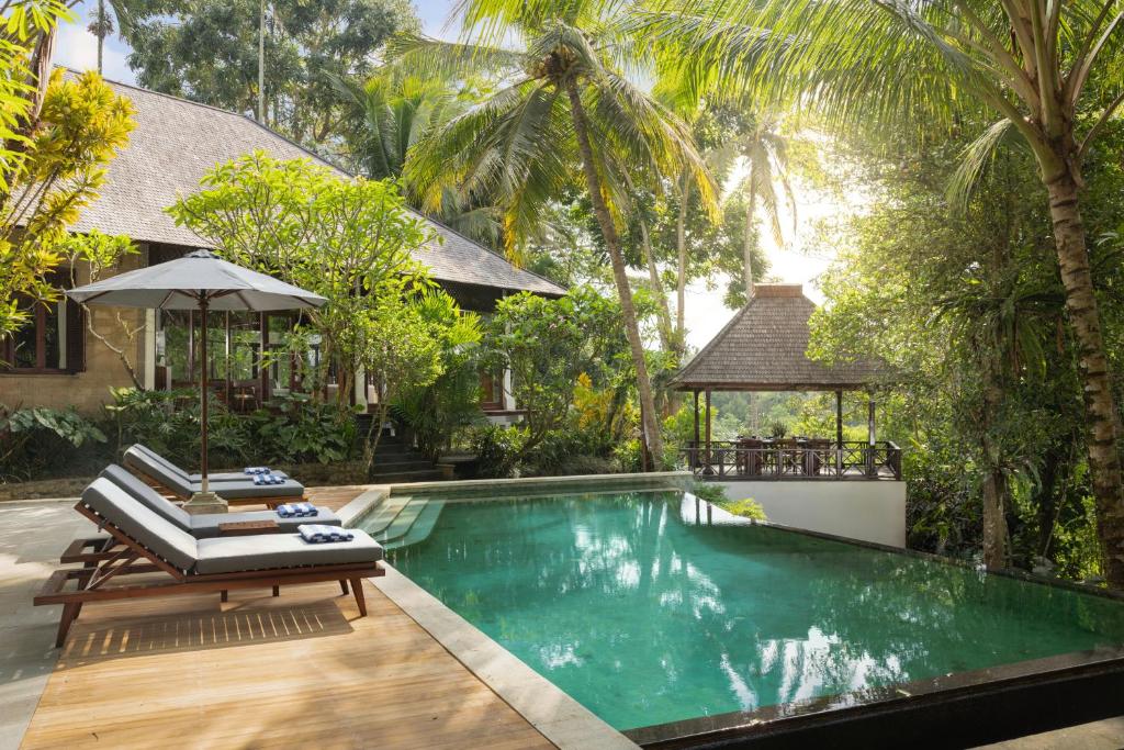 a swimming pool with two lounge chairs and an umbrella at Villa Leona Ubud in Ubud