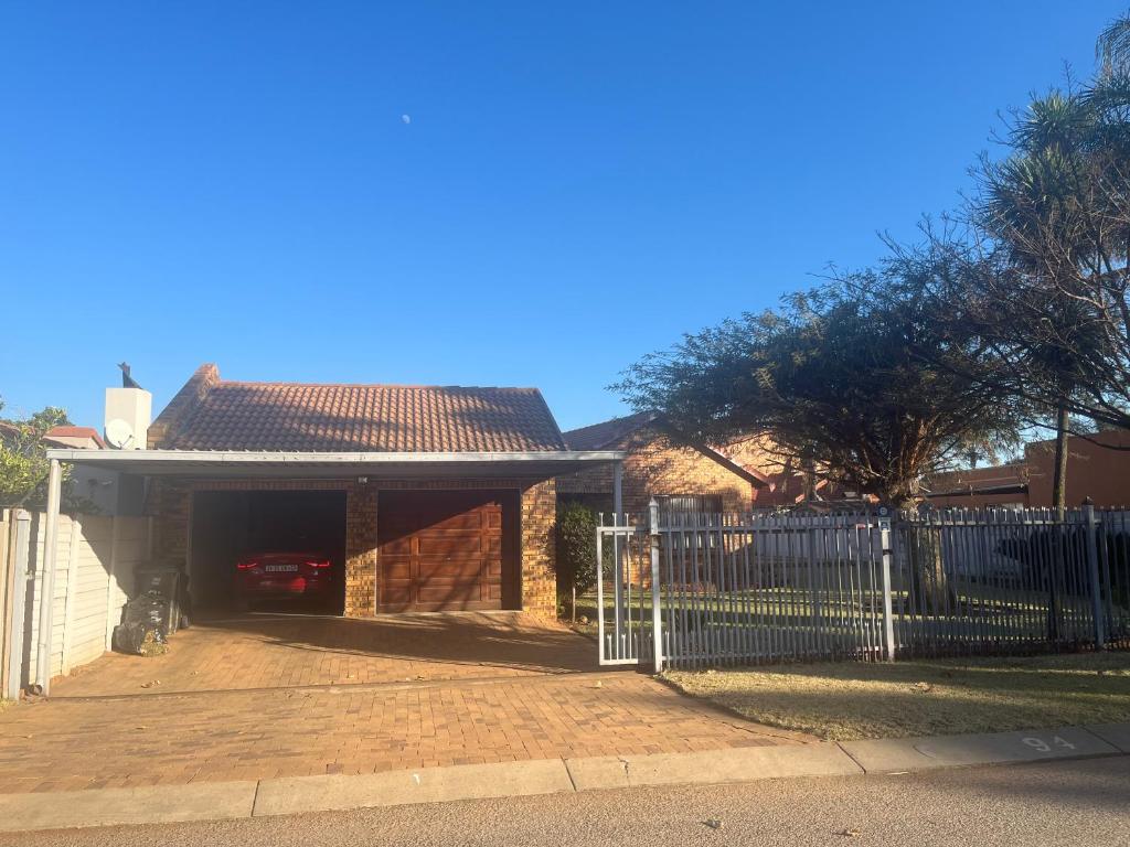 a fence in front of a house with a garage at Centurion Family House in Centurion