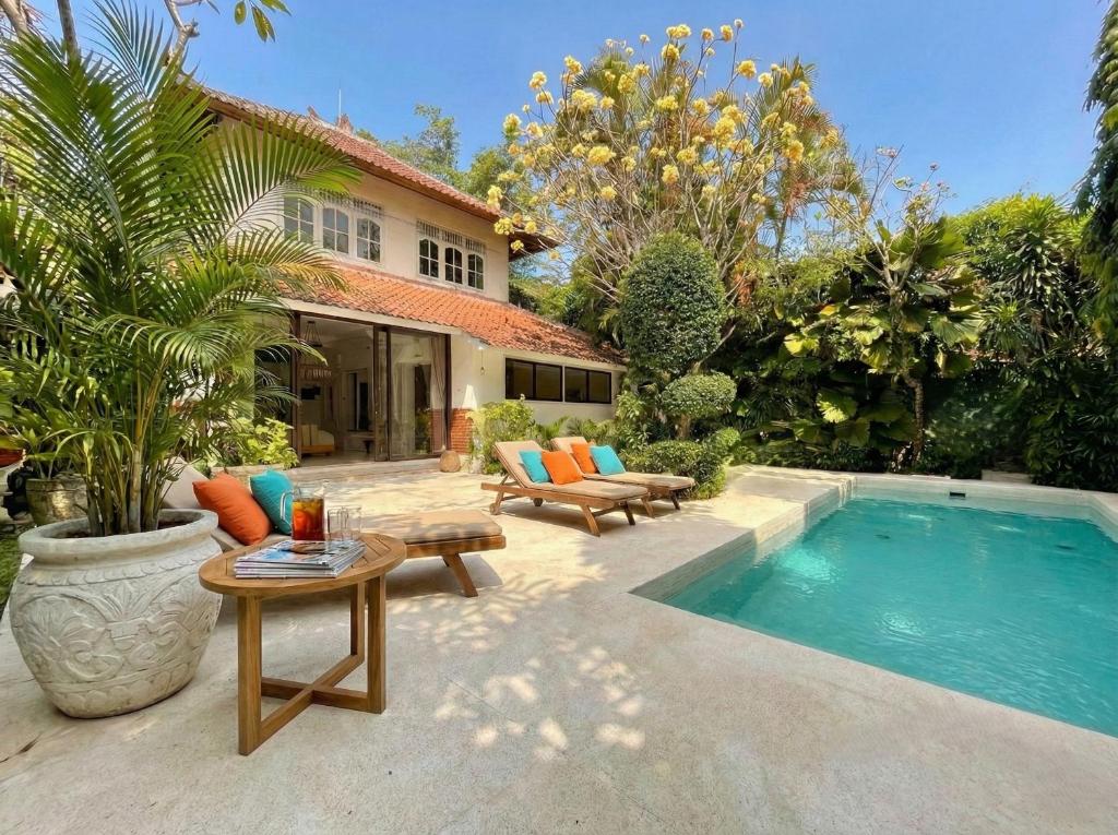 a backyard with a swimming pool and a house at White Orchid Villa Seminyak in Seminyak