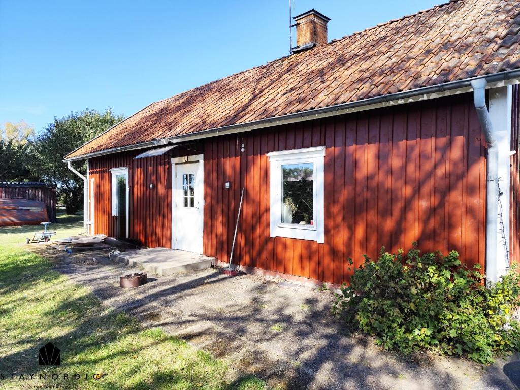 a red barn with a white door and a yard at Charming red cottage in Vaderstad SE10024 in Väderstad