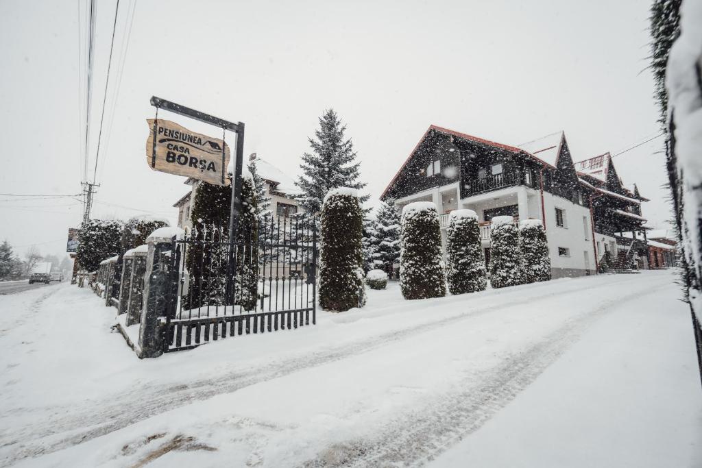 een met sneeuw bedekte straat met een hek en een huis bij Pensiune Borsa in Borşa
