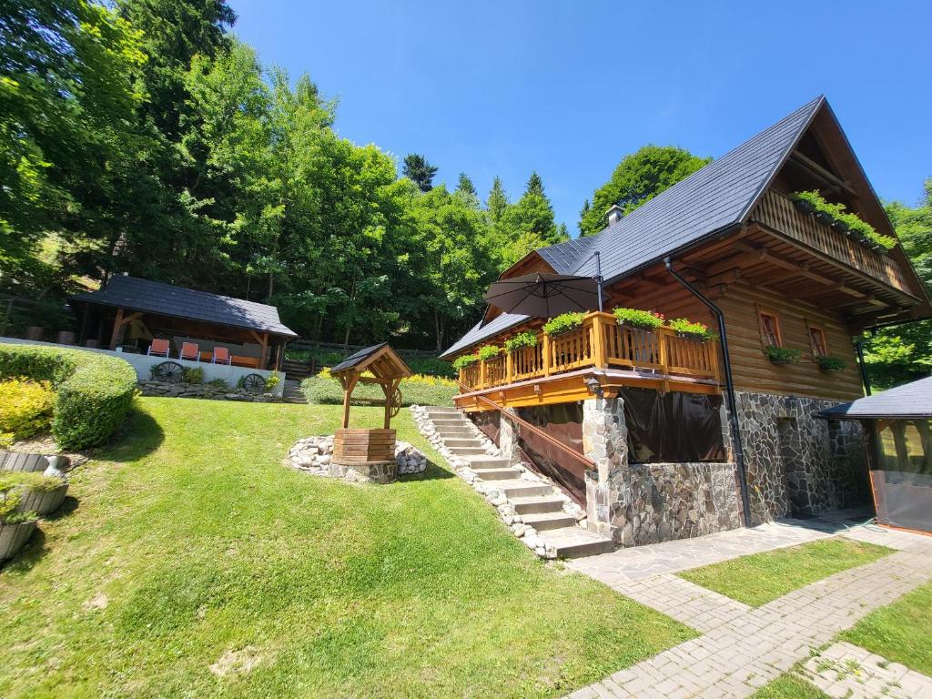 a log cabin with a deck on the grass at Chata pod Kykulou in Oščadnica