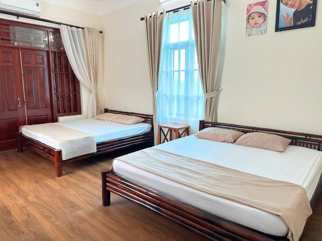 a bedroom with two beds and a window at Ecohost Hai Trung in Háº£i Háº­u