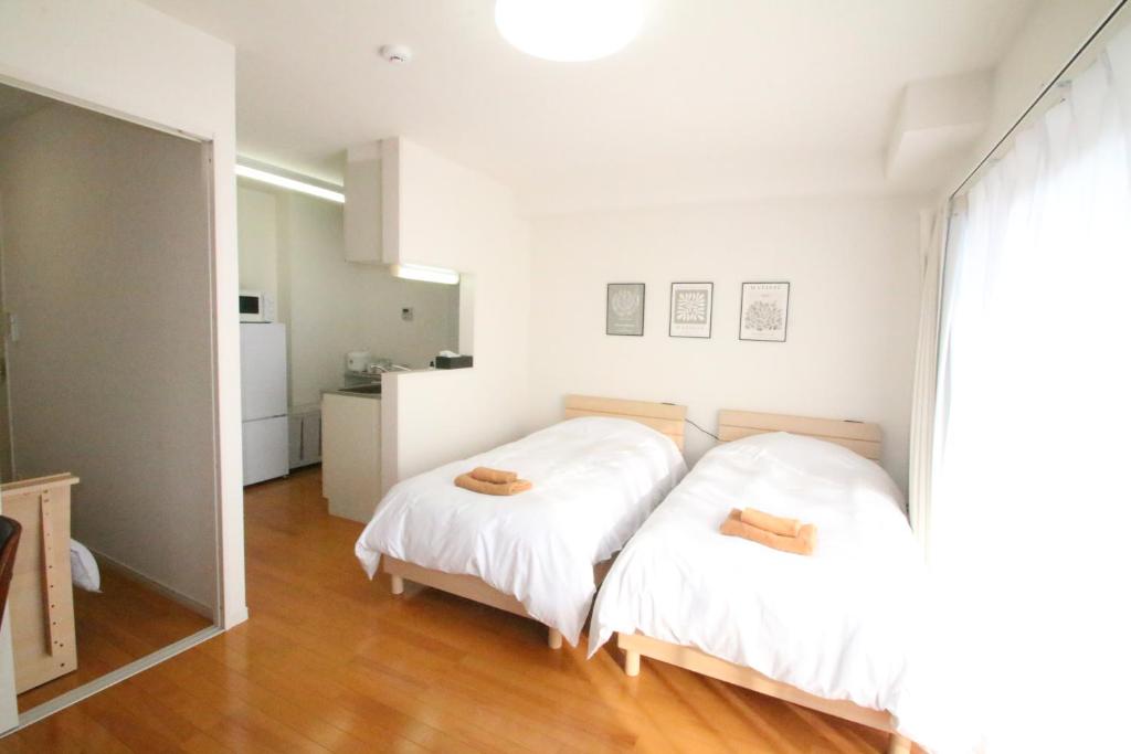a bedroom with two beds with white sheets at オンブラージュ704号室-無料駐車場付き-繁華街まで徒歩圏内-南向きで明るいワンルーム in Kumamoto