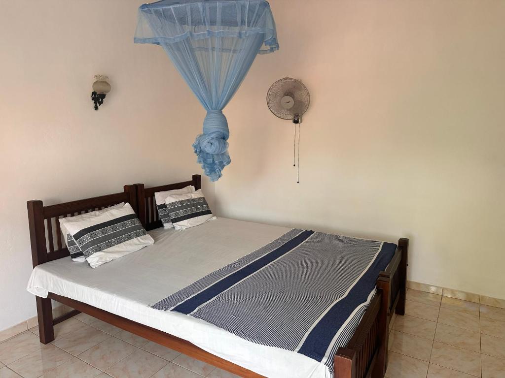a bedroom with a bed with a blue curtain at Chamila's place in Nikawatawana
