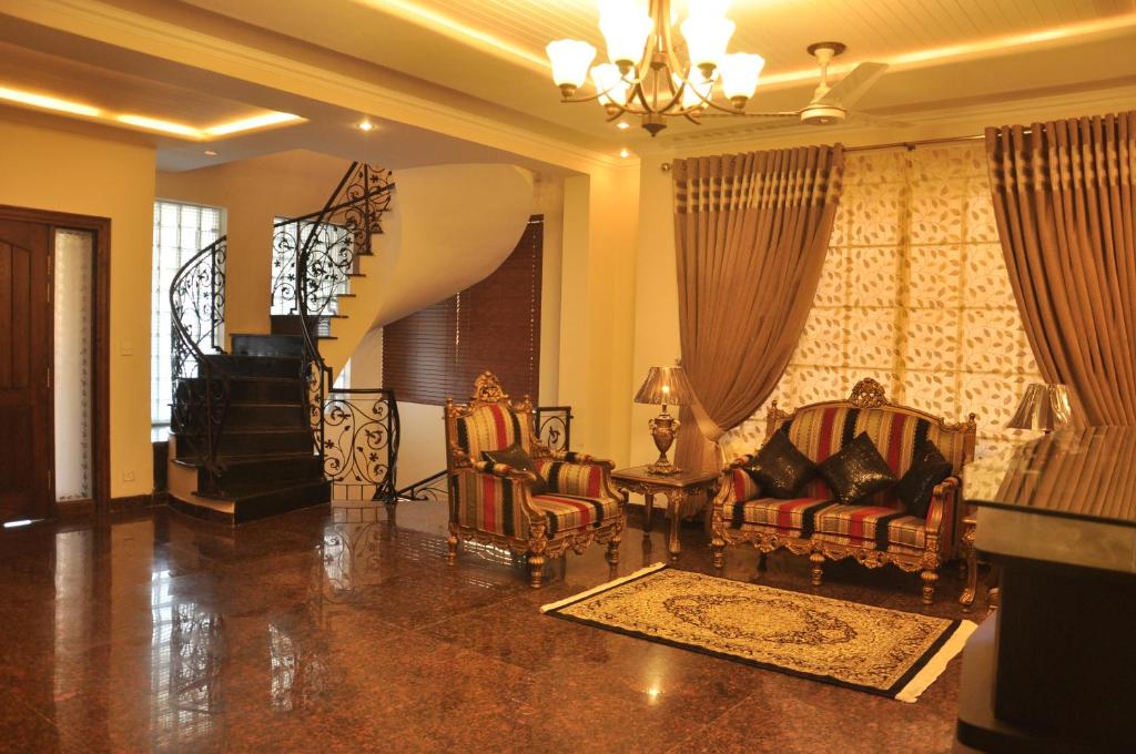 a living room with two chairs and a staircase at Reina Boutique Hotel - G9 in Islamabad