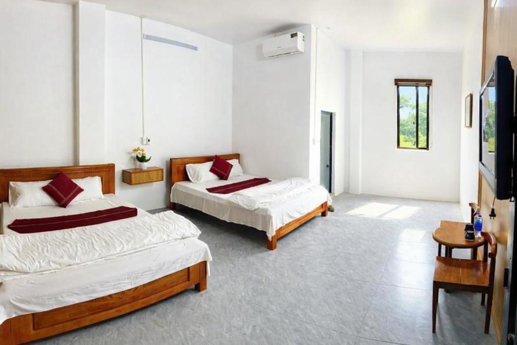 een slaapkamer met twee bedden en een televisie bij Bảo Ngọc Motel in Ha Giang