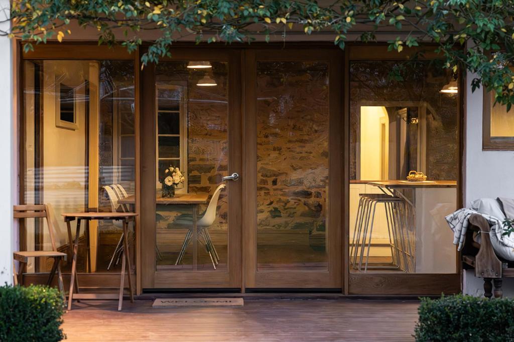 a glass door to a patio with a table and chairs at Thedell Cottage - A Boutique Heritage Escape in Auburn