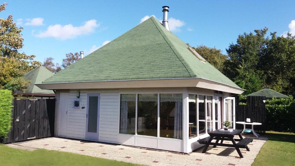 een kleine witte schuur met een groen dak bij Bungalowpark De Toekomst in Ouddorp