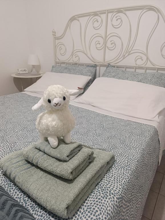 a stuffed lamb sitting on a pile of towels on a bed at Su Planu in Cagliari