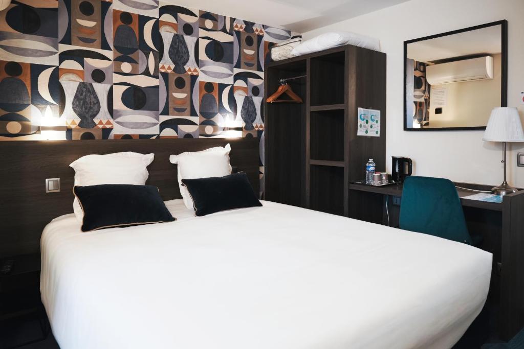 een slaapkamer met een groot wit bed met een muur bij Brit Hotel Confort Orly Morangis in Morangis