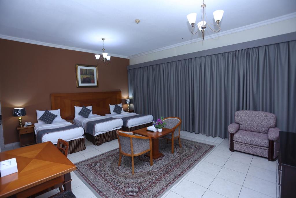 a hotel room with two beds and a table at Icon Hotel Apartments in Dubai