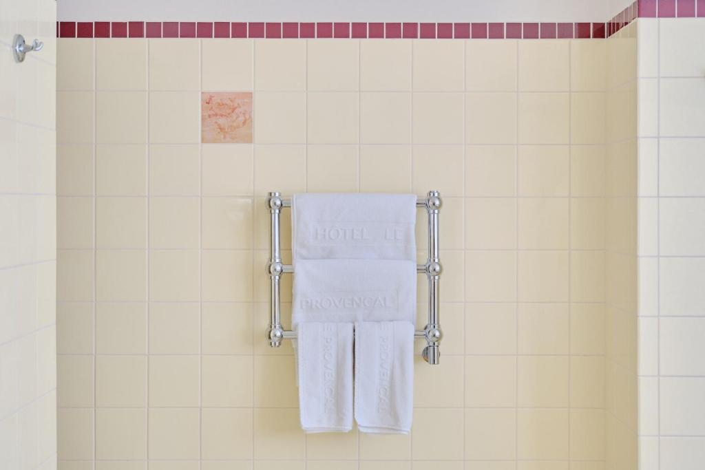 een handdoek die in een douche met witte tegels hangt bij Hôtel Le Provençal - Rénové en 2025 - Bord de Mer in Hyères