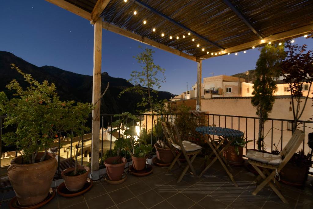a patio with potted plants and a fence with lights at The Tile House in Güéjar-Sierra