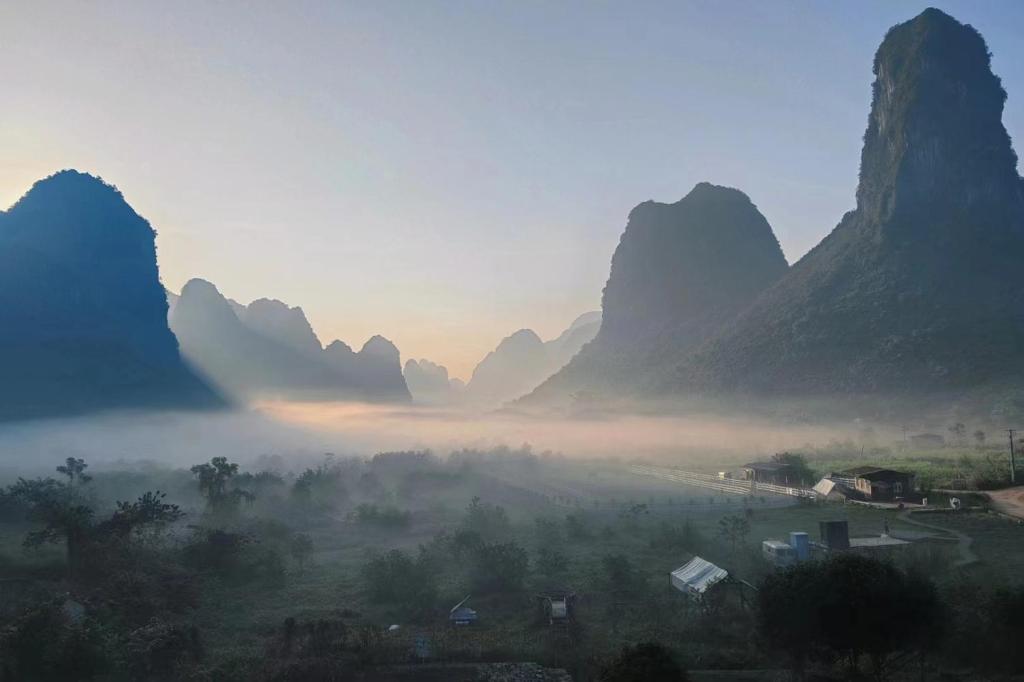 una valle nebbiosa con montagne sullo sfondo di Hidden Valley Hotel a Yangshuo