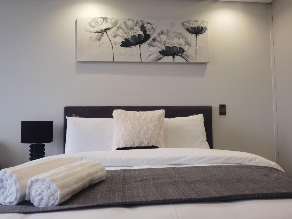 a bedroom with a bed with a picture on the wall at Ellipse Luxurious Tamarind Red Studio Experience in Midrand