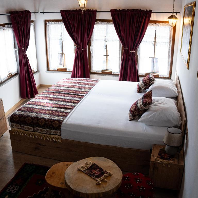 a bedroom with a large bed with red curtains at Hotel Ari Old Town in Gjakove