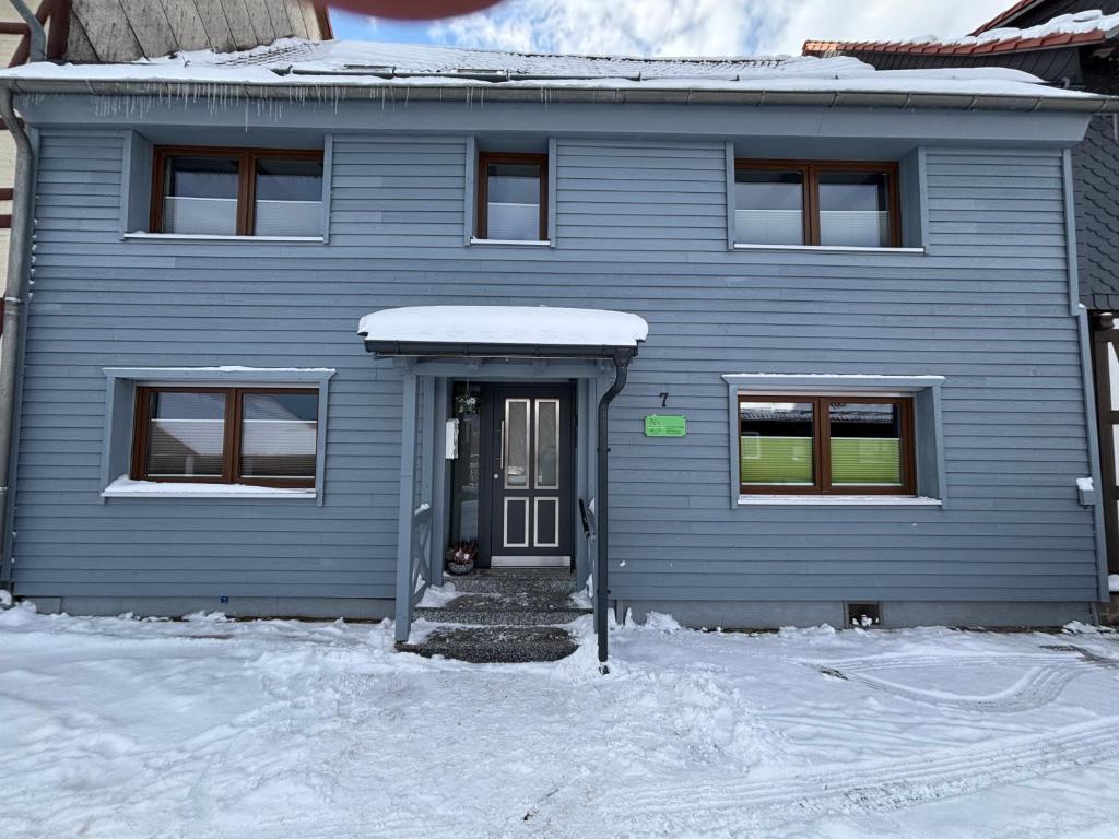 een blauw huis met een deur in de sneeuw bij Am Graben 2 in Hasselfelde