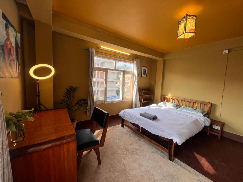 a bedroom with a bed and a desk and a window at Sunny Side Up top-floor apartment in Kathmandu
