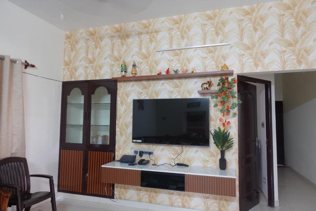 a living room with a flat screen tv on a wall at Thiruveesar Family Retreat near Airport in Tiruchirappalli