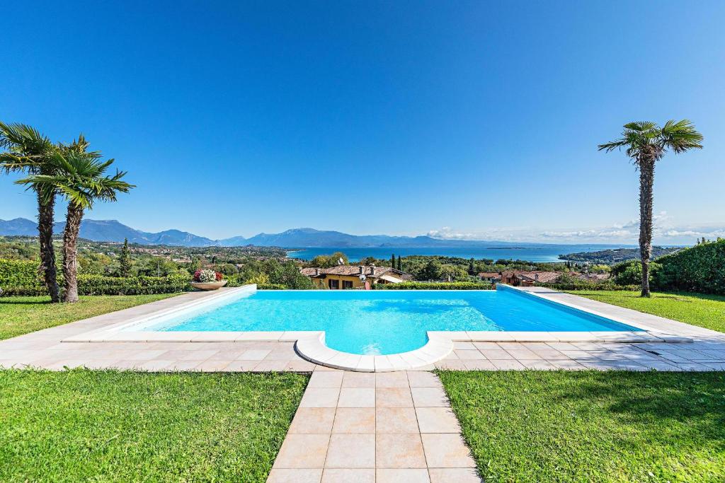 a swimming pool in a yard with palm trees at Villa Perla by Whale Homes in Lonato