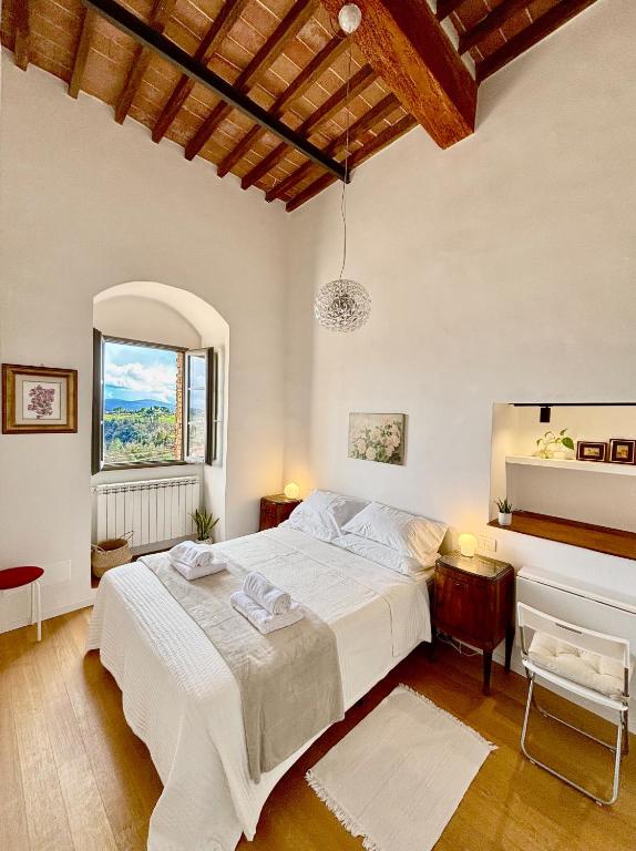 a bedroom with a large white bed and a window at La Torre di Canonica in Colle di Val d'Elsa