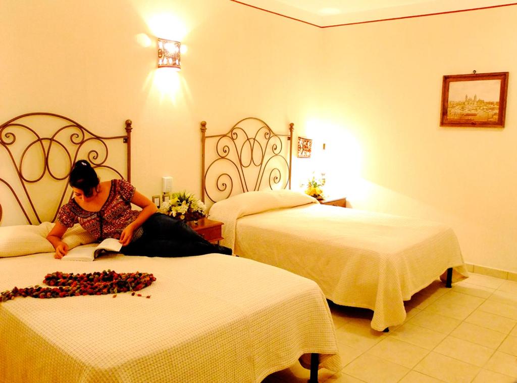 une femme assise sur un lit dans une chambre d'hôtel dans l'établissement Hotel Dainzu, à Oaxaca