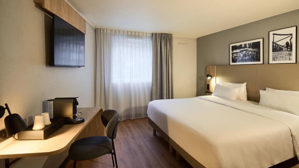 una camera d'albergo con un letto e una scrivania di Campanile PRIME - Arcueil ad Arcueil