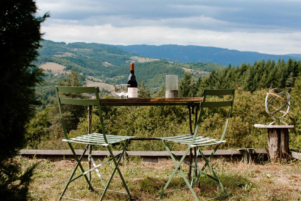 a table with a bottle of wine and two chairs at Les Meules in Saint-Basile